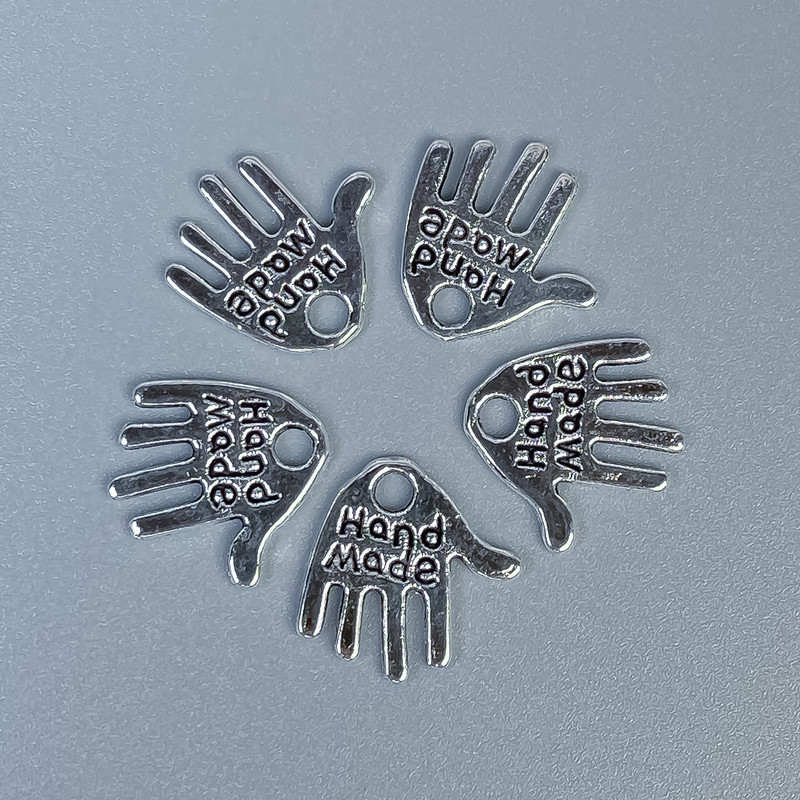 Přívěšek ve tvaru dlaně, ručně vyrobený, barva kovu stříbrná, rozměry 12×11×1 mm ± otvor, průměr 1,5 mm ± balení 20 g (~50 ks).