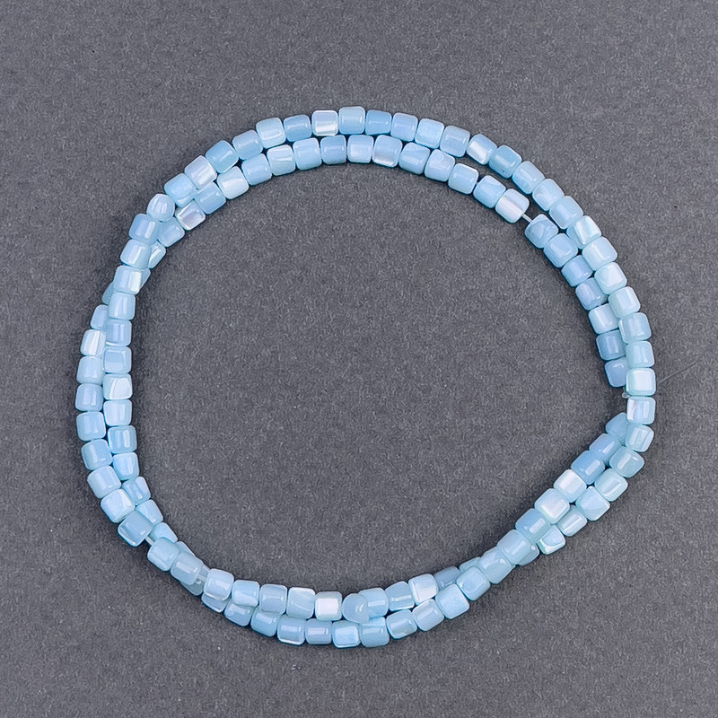 Korálky z tónované modré perleti cylindrického tvaru, průměr 3,5 × 3,5 mm, délka 40 cm ± na niti